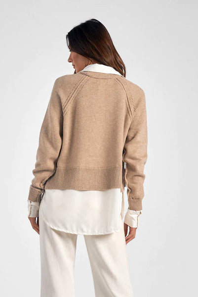 Taupe and white sweater and blouse top being worn by a woman in front of a white background. Showcasing the longer hem giving various body types that comfortability of wearing this top