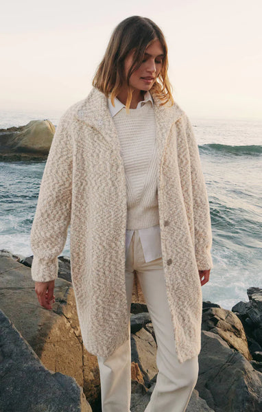 Woman wearing the Z Supply Connor coat standing on rocks by the ocean. The Z Supply Connor Coat is ivory color with a beautiful soft texture. Perfect transitional jacket for fall into winter. Available now at Marigold Boutique in Midland Park NJ.